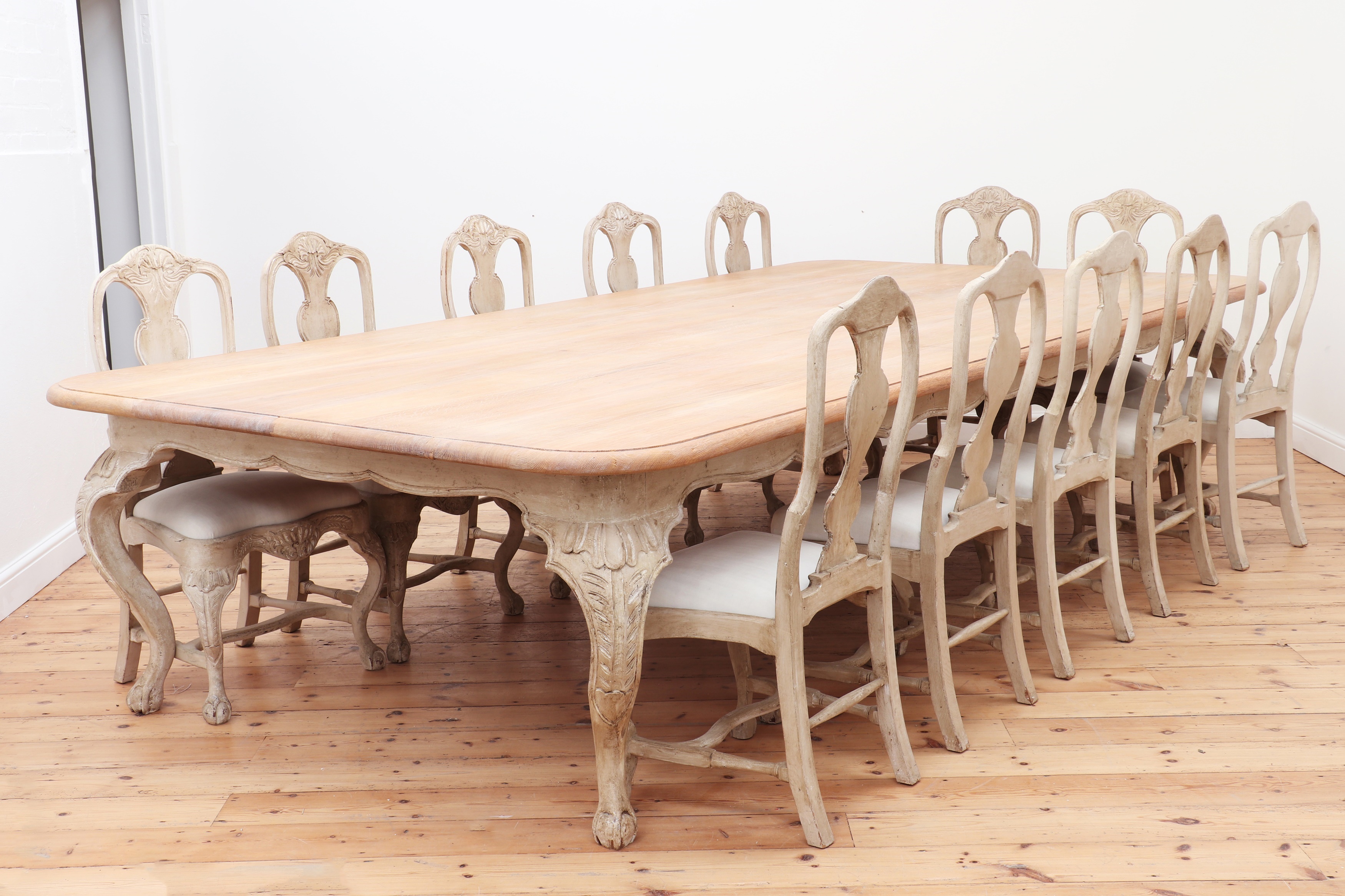A large limed oak dining table by Augustus Brandt, together with a set of eighteen matching dining chairs